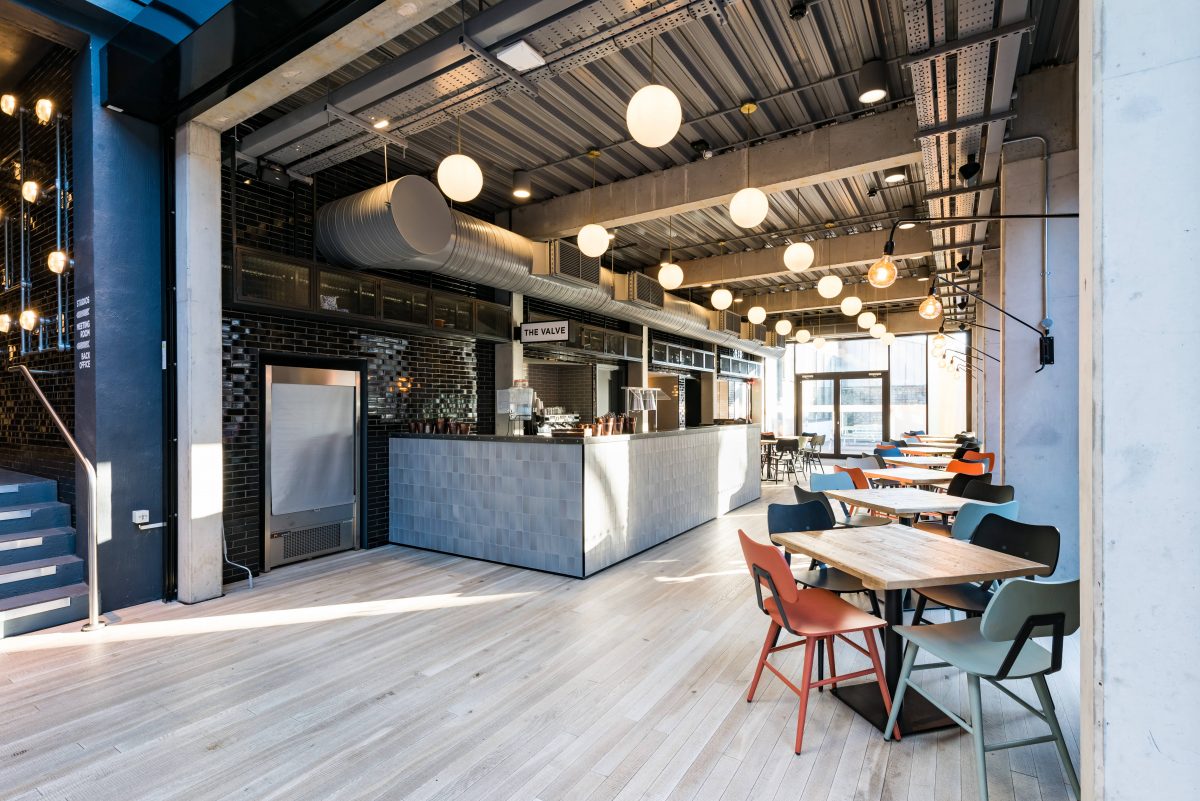 modern blue and grey coffee shop with orange, grey, and blue chairs and square table